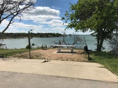 Picnic table, grill, and fire ring with Waco Lake in the background