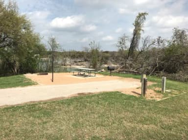 Picnic table, grill, and fire ring with Waco Lake in the background