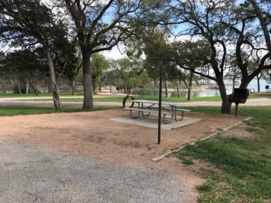 Picnic table, grill, and fire ring with Waco Lake in the background