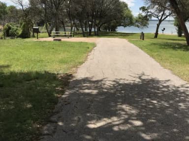 RV site with picnic table, grill, fire ring, and Waco Lake in the background