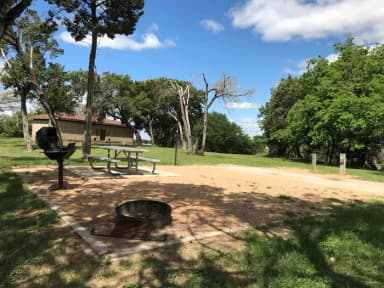 Picnic table, grill, and fire ring with restroom/shower facilities in the background