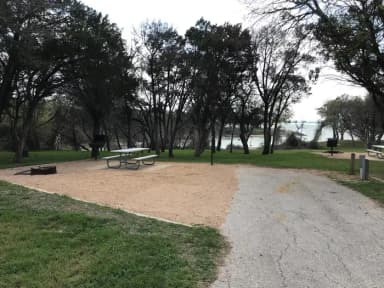 Picnic table, grill, and fire ring with Waco Lake in the background