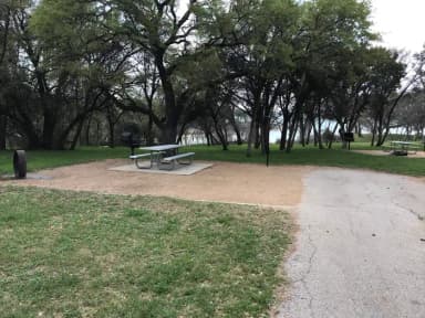 Picnic table, grill, and fire ring with Waco Lake in the background
