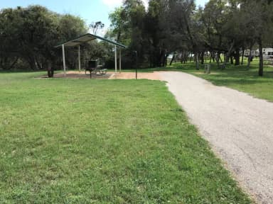 RV site with covered picnic table, grill, and fire ring