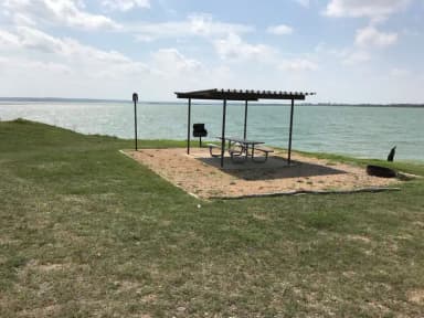 Tent site with picnic table, grill, and fire ring.  Site is located very close to shoreline of Waco Lake