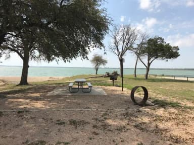 Tent site with picnic table, grill, and fire ring.  Site is located very close to shoreline of Waco Lake