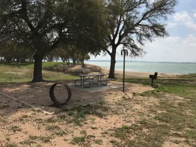 Tent site with picnic table, grill, and fire ring.  Site is located very close to shoreline of Waco Lake