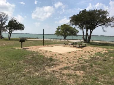 Tent site with picnic table, grill, fire ring, and Waco Lake in the background
