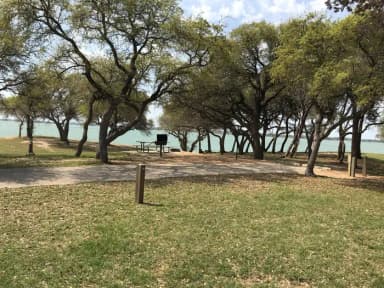 RV site with picnic table, grill, fire ring, and Waco Lake in the background