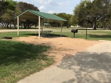 RV site with covered picnic table, grill, and fire ring