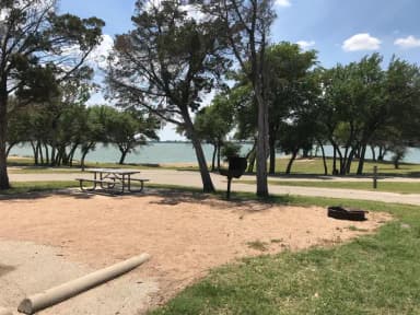 Picnic table, grill, and fire ring with Waco Lake in the background