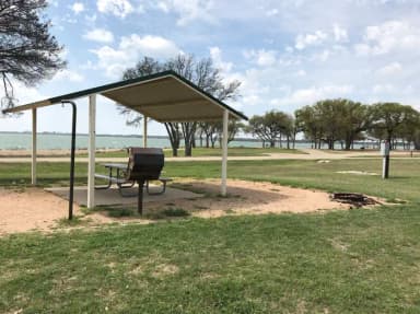 Covered picnic table, grill, fire ring, and Waco Lake in the background