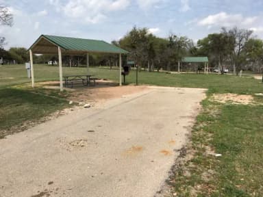 RV site with covered picnic table, grill, and fire ring