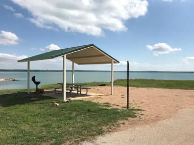 Covered picnic table, grill, fire ring, and Waco Lake in the background