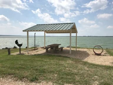Tent site with covered picnic table, grill, and fire ring.  Site is located very close to shoreline of Waco Lake