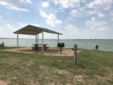 Tent site with covered picnic table, grill, and fire ring.  Site is located very close to shoreline of Waco Lake