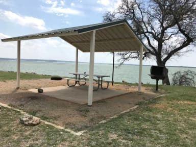 Tent site with covered picnic table, grill, and fire ring.  Site is located very close to shoreline of Waco Lake