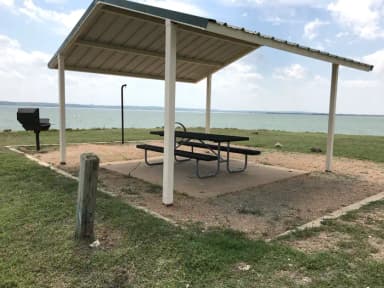 Tent site with covered picnic table, grill, and fire ring.  Site is located very close to shoreline of Waco Lake