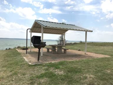 Tent site with covered picnic table, grill, and fire ring.  Site is located very close to shoreline of Waco Lake