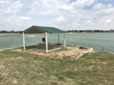 Tent site with covered picnic table, grill, and fire ring.  Site is located very close to shoreline of Waco Lake