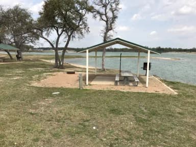 Tent site with covered picnic table, grill, and fire ring.  Site is located very close to shoreline of Waco Lake