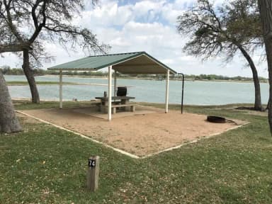 Tent site with covered picnic table, grill, and fire ring.  Site is located very close to shoreline of Waco Lake