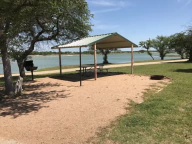 Covered picnic table, grill, fire ring, and Waco Lake in the background