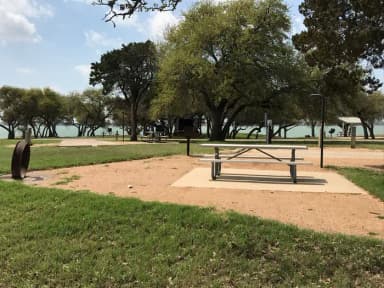 RV site with picnic table, grill, fire ring, and Waco Lake in the background