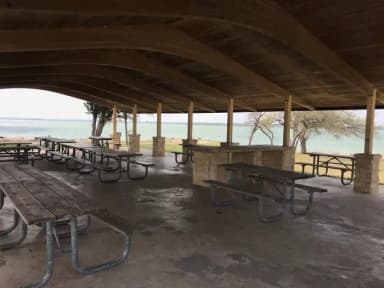 Picnic tables under the pavilion with Waco Lake in background