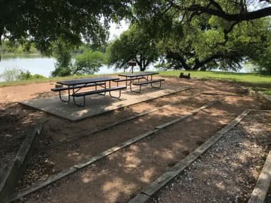 Picnic tables, grill, and fire ring with Waco Lake in the background