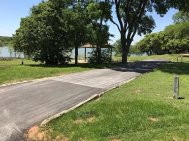 RV site with covered picnic table, grill, fire ring, and Waco Lake in the background