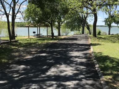 RV site with covered picnic table, grill, fire ring, and Waco Lake in the background