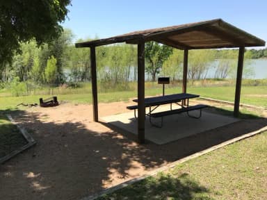 Covered picnic table, grill, and fire ring with Waco Lake in the background