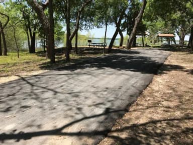RV site with picnic table, grill, fire ring, and Waco Lake in the background