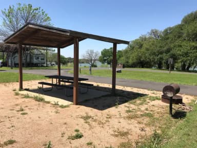 Covered picnic table, grill, and fire ring with Waco Lake in the background