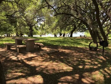 Tent site with picnic table, grill, and fire ring with Waco Lake in the background