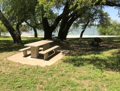 Tent site with picnic table, grill, and fire ring with Waco Lake in the background