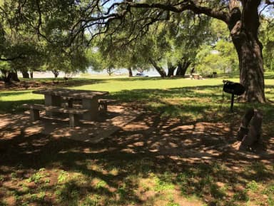 Tent site with picnic table, grill, and fire ring with Waco Lake in the background