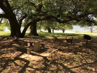 Tent site with picnic table, grill, and fire ring with Waco Lake in the background