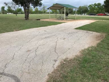 RV site with covered picnic table, grill, fire ring, and Waco Lake in the background