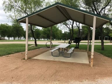 Covered picnic table, grill, and fire ring with Waco Lake in the background