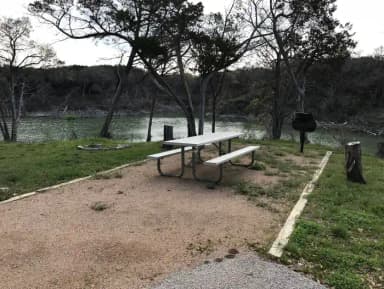 Picnic table, grill, and fire ring with Waco Lake in the background