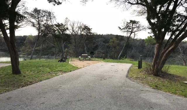 RV site with picnic table, grill, fire ring, and Waco Lake in the background