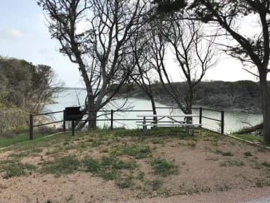 Picnic table and grill at site with Waco Lake in the background