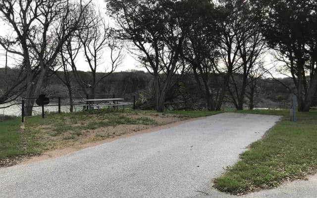 RV site with picnic table, grill, and Waco Lake in the background