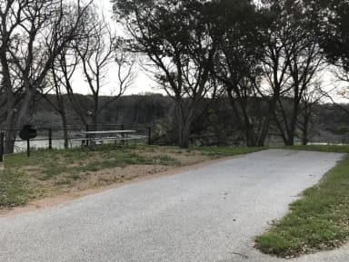 RV site with picnic table, grill, and Waco Lake in the background