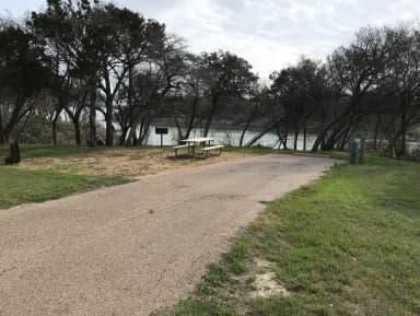 RV site with picnic table, grill, fire ring, and Waco Lake in the background