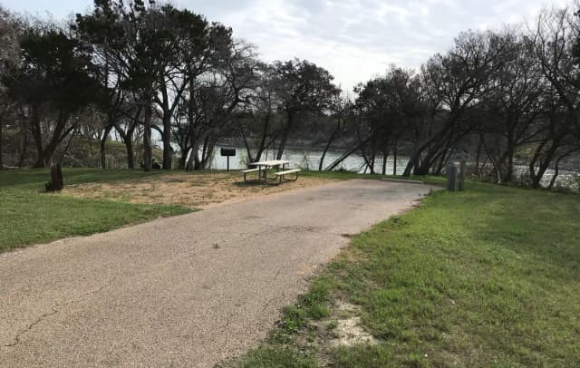 RV site with picnic table, grill, fire ring, and Waco Lake in the background