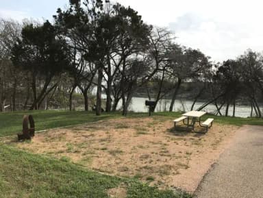 Picnic table, grill, and fire ring with Waco Lake in the background