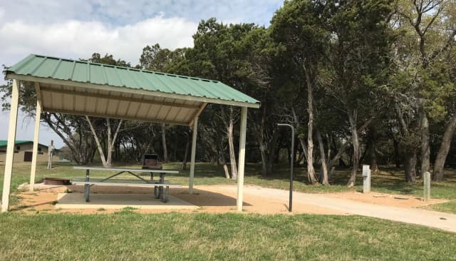 RV site with covered picnic table, grill, fire ring, and restroom/shower facilities nearby
